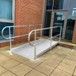 A durable bespoke wheelchair ramp installed over the front steps of a domestic home.